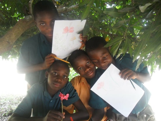 A group of four students holding papers and flowers